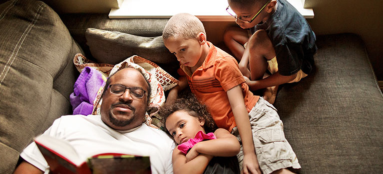 Father reading a book to children